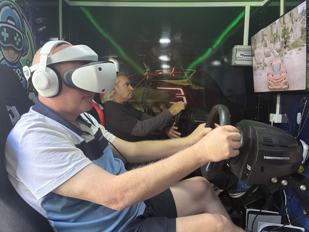 Participant wearing a PSVR2 headset in a racing cockpit for a unique corporate team building Sydney event inside a mobile gaming trailer.